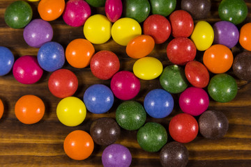 Colorful button shaped candies filled with chocolate on wooden table
