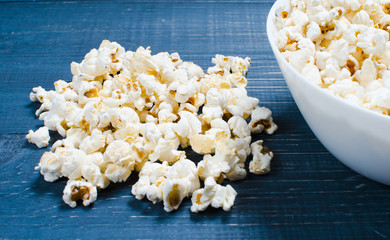 Salty popcorn lies on a wooden background. The concept of cinema. Watch a movie with friends and...