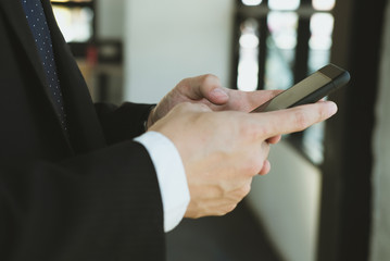 Obraz premium businessman holding smartphone & using app at office. man texting message at workplace. social network communication, wireless connection, lifestyle concept