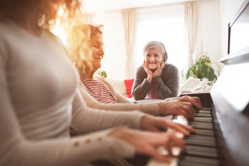 A girl with mother and grandmother playing the piano.