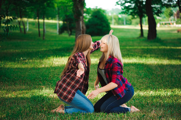 Fototapeta premium two young women sitting on grass hugging