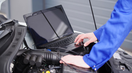 Mechaniker arbeitet mit einem Laptop an einem Auto, Motorsteuerung 