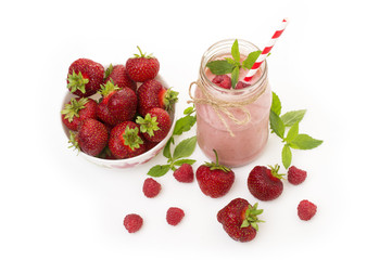 Pink strawberry and raspberry smoothie in a mason jar glass with straw and scattered berries