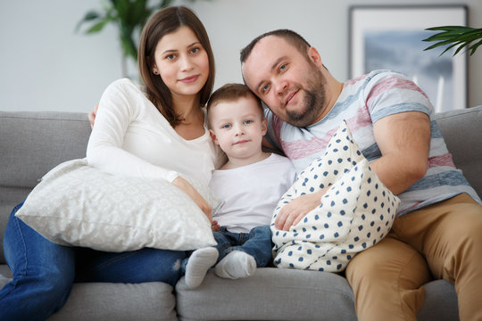 Image of hugging family with son on gray sofa