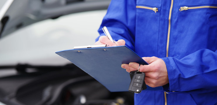 Mechaniker bei der Durchsicht eines Autos, T&Uuml;V-Untersuchung 