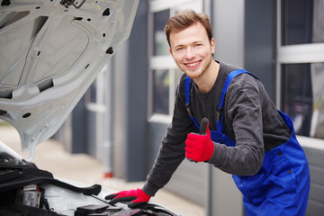 Automechaniker sympathisch lächelnd inspiziert einen Motor 