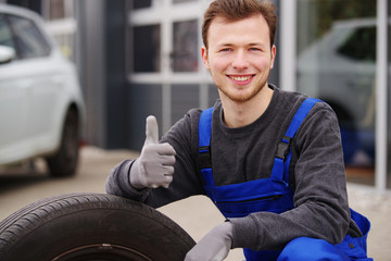 Mechaniker mit einem Auto-Reifen, Radwechsel 