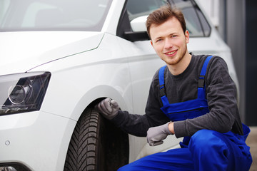 Automechaniker  / Automechatroniker vor einer Auto-Werkstatt 