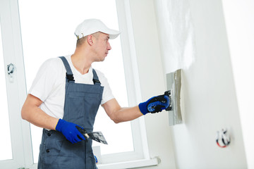 Plastering. Worker spackling a wall with putty
