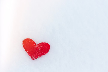 Obraz premium red felt heart figure on snow, winter day with sun glare