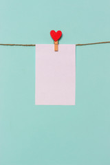 white piece of paper pinned to rope with clothespin decorated with wooden heart