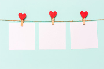 white pieces of paper pinned to rope with clothespins decorated with wooden hearts