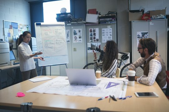 Businesswoman giving presentation to coworker over flip chart