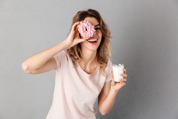 Woman in t-shirt having fun while holding donut and milk
