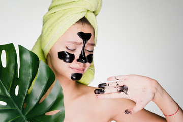 woman with a towel on her head applied a mask to problem areas of the face