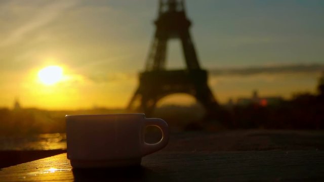 White cup of coffee on a sunny morning in the background of the Eiffel Tower