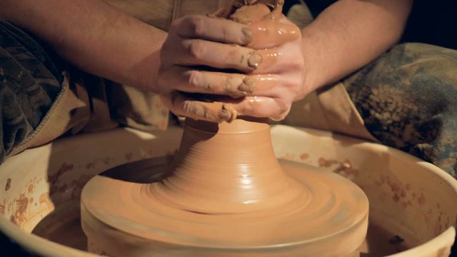 A close view on potters hands throwing a vase. 