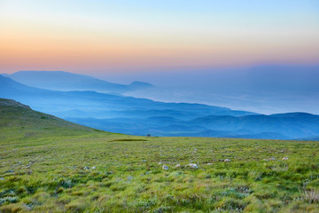 Sunset in the mountains with rocks and green grass