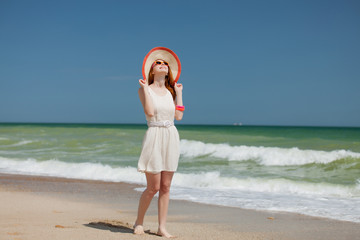 Naklejka premium oung redhead girl in hat at sea beach