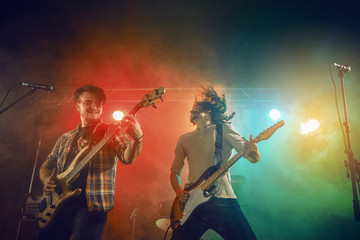 Fototapeta premium Rock band performs on stage. Guitarist, bass guitar and drums.