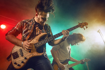 Rock band performs on stage. Guitarist, bass guitar and drums.