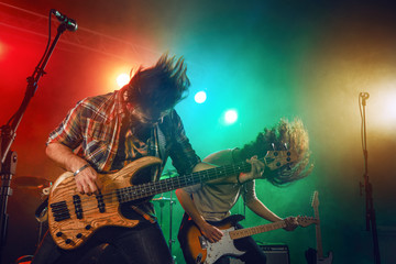 Rock band performs on stage. Guitarist, bass guitar and drums.