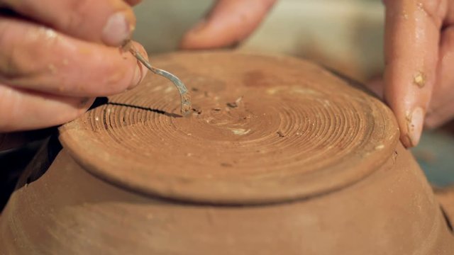 A detailed view on a potter cutting his signature on a bowls bottom surface. 