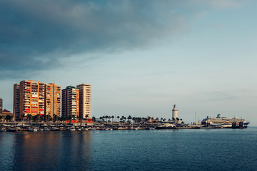 Fototapeta na wymiar city on the sea. City Waterfront with buildings, lighthouse and ship. Porto of Malaga, Spain.