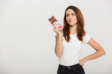 Portrait of a pensive young woman looking at chocolate bar