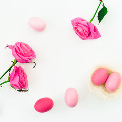 Pink Easter egg and quail eggs in nest and pink roses on white background. Top view, Fat lay. Easter holiday concept.