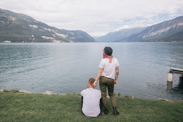 back view of young couple looking at majestic mountain lake in Bern, Switzerland