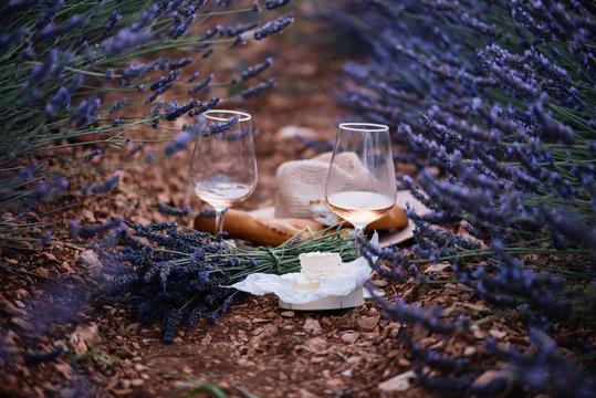 Fototapeta Aged camembert cheese, freshly baked baguettes, two glasses of rose wine and a bouquet of freshly picked lavender-picnic in the lavender field, summer Provence, south France