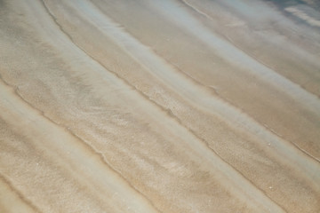 Figure in the form of curved lines in the sand on the beach, make waves