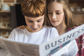 close-up portrait of young lesbian couple reading newspaper together