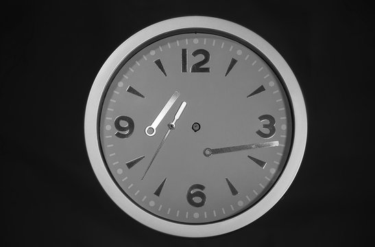 Runde Wanduhr mit verwirrenden, losen Zeigern und schwarzem Hintergrund