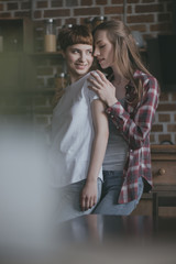 smiling young lesbian couple on kitchen at home