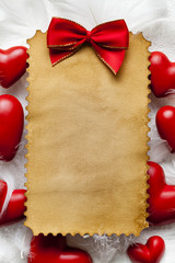 Blank handmade paper sheet, red bow and red hearts on white background