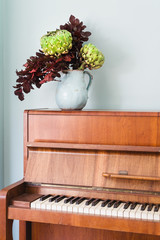 rustic vase with artichoke flower on piano