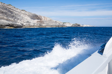 Cliffs near Bonifacio as seen from a boat with splashes in Corsica, France