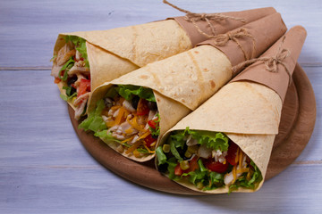 Wraps with chicken, tomatoes, lettuce, black beans, cheddar cheese and sweet corn. Tortilla, burritos, sandwiches twisted rolls. horizontal