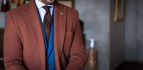 Man in custom tailored suit and trench coat posing indoors