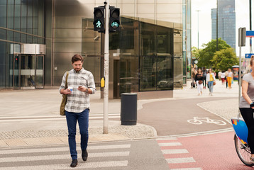 Young man walking through the city using a cellphone