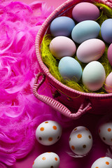 Painted Easter eggs in a basket and pink feathers