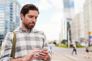 Young man standing in the city using a cellphone