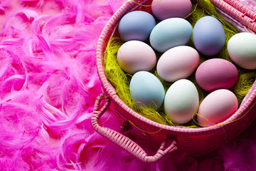 Fototapeta na wymiar Easter background - colored eggs and feathers on pink background