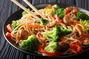 Japanese food: Soba noodles with mushrooms, broccoli, carrots, peppers close-up on a plate on the table. horizontal
