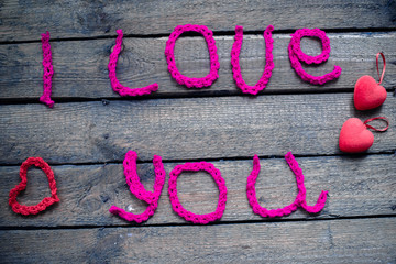 Inscription in knitted letters on a wooden background. Valentine's Day