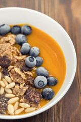 puree of mango with granola, chia and berries in white bowl