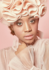 Close-up portrait of beautiful black woman with light hair and green eyes wearing powder pink tulle...