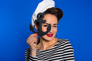 portrait of fashionable young woman in retro clothing with anchor in hand isolated on blue